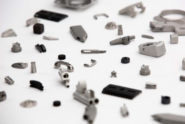 A collection of various small metallic machine parts and tools scattered on a white surface.
