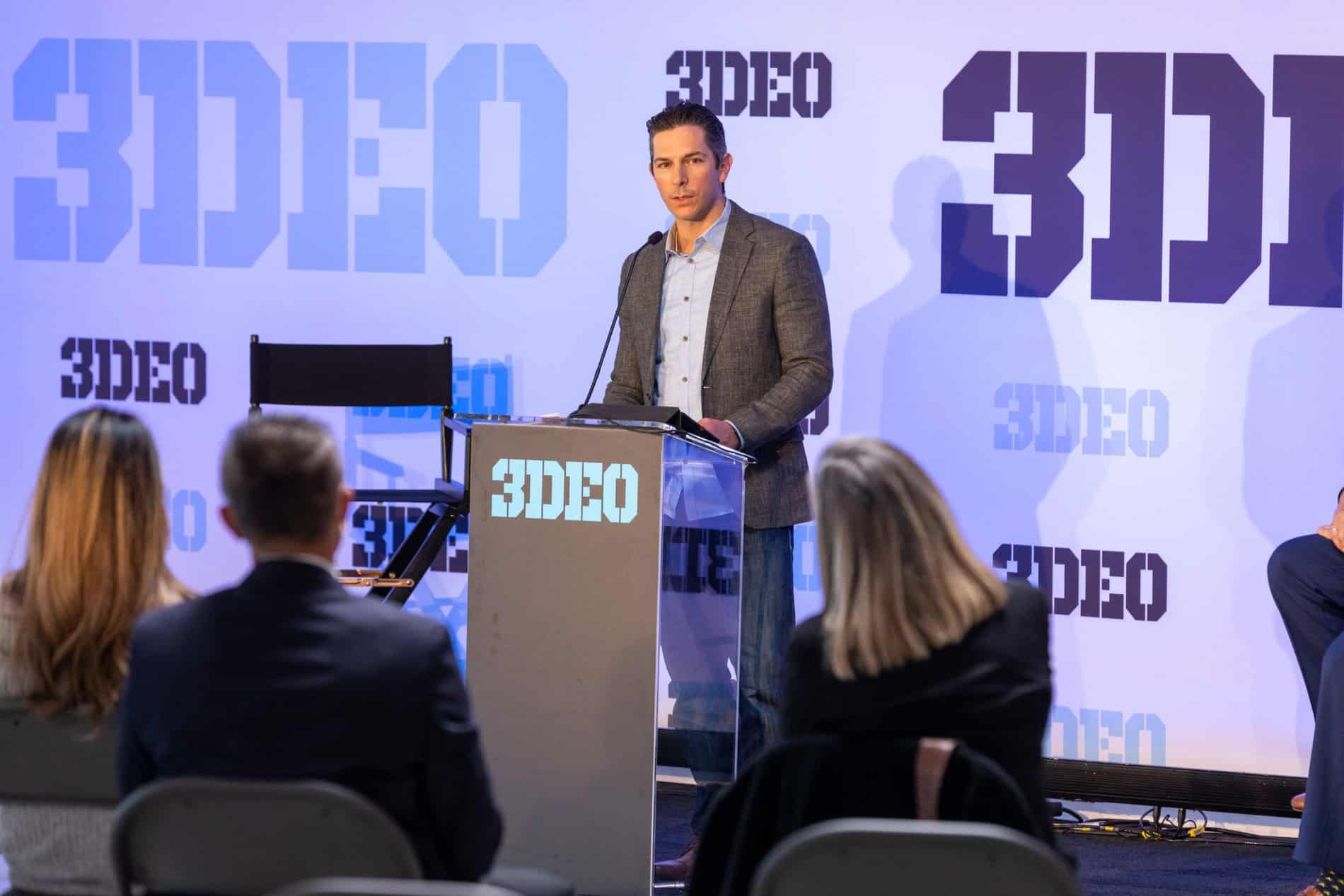 3DEO Hosts Press Conference: Unveils New Saffron Printer & Technology A man stands at a podium labeled "3deo" presenting to an audience in a conference room with "3deo" graphics in the background.