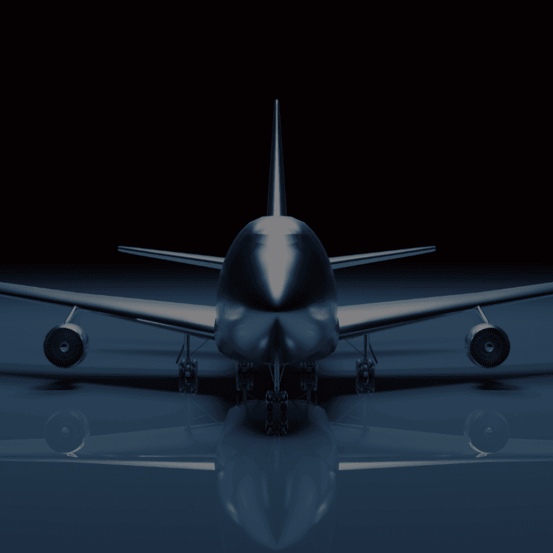 Front view of a large airplane with its landing gear down, set against a dark background with a slight reflection on the ground.