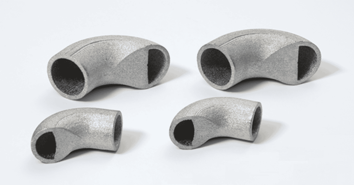 3DEO Wins Grand Prize at 2024 Design Excellence Awards Four metallic elbow pipe fittings of varying sizes are arranged on a white surface, showcasing the precision craftsmanship often seen in aerospace applications.